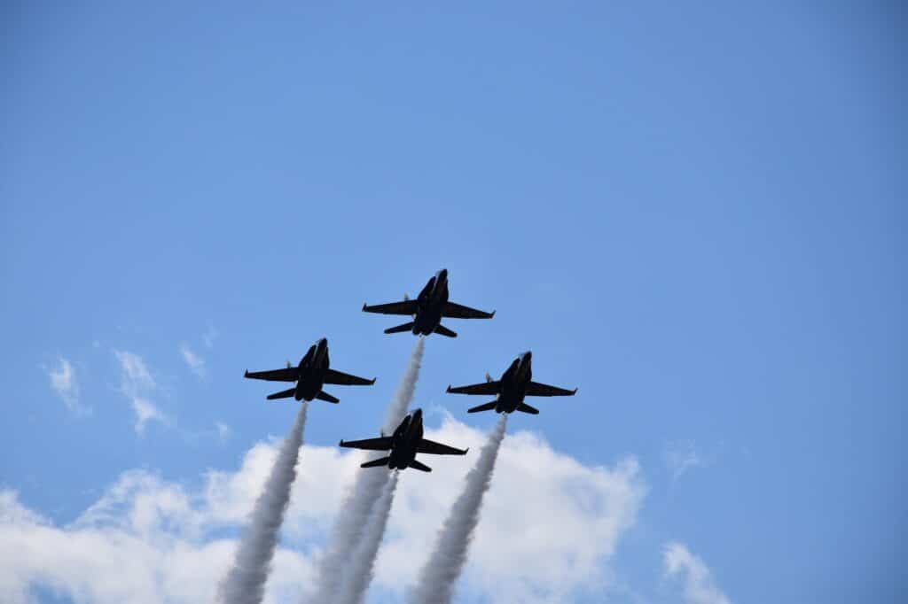 Low angle shot of four fighter jets with big trails maneuvring in the sky during an air show